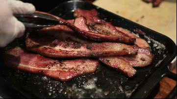 Imagem ilustrativa de pessoa cozinhando bacon - Getty Images